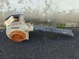 a small blower sitting on the ground next to a concrete wall
