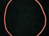 a coral beaded necklace with a silver clasp on a black background