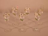 four wine glasses with flowers on them are lined up on a table