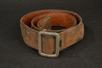 brown leather belt with a metal buckle on a black background
