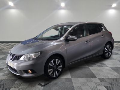 La Nissan Versa argentée est garée dans une pièce dont le sol est à carreaux.