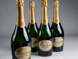 four bottles of champagne are lined up on a table