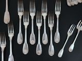 a lot of forks and spoons on a black table