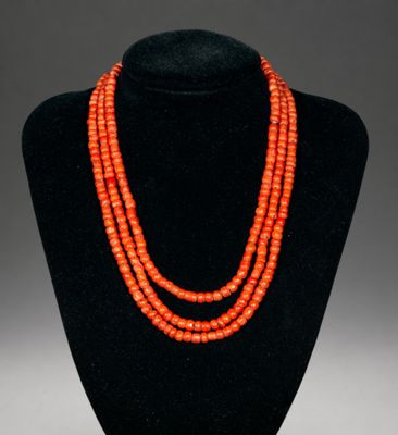an orange beaded necklace on a black mannequin