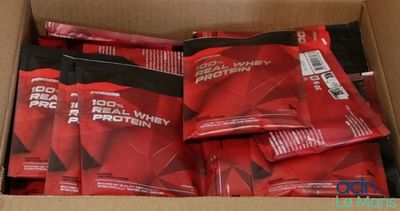 des sachets rouges de protéines dans une boîte en carton posée sur une table