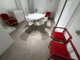 une table blanche et des chaises rouges dans une petite pièce