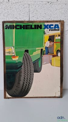 une image représentant un camion vert sur lequel est posé un pneu
