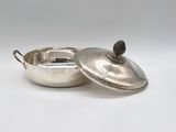an antique silver plated casserole with a lid on a white background