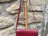 a red purse hanging on a wooden pole next to a stone wall