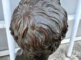 a bronze statue of a boy with a short hair
