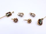 five pairs of earrings and a broocher on a white surface