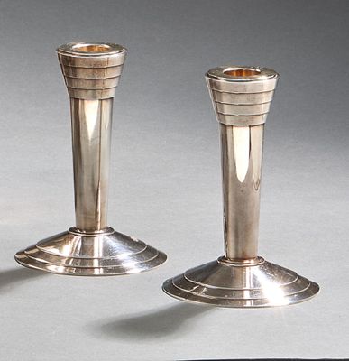 deux bougeoirs en argent posés l'un à côté de l'autre sur une table