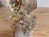 a figurine of a bird on a branch with flowers