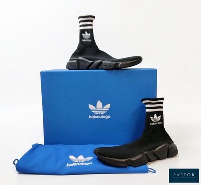 Des chaussures adidas et un sac bleu sont posés sur une surface blanche