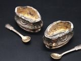 two silver spoons and a spoon rest on a black surface