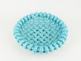 a close up of a blue beaded bowl on a white surface