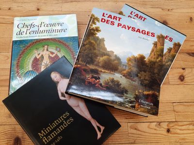 trois livres posés sur une table en bois