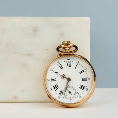 une montre de poche en or posée sur un bloc de marbre