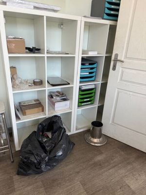 a trash bag sitting on the floor in front of a bookcase