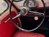 un volant et un tableau de bord de voiture avec des sièges en cuir rouge