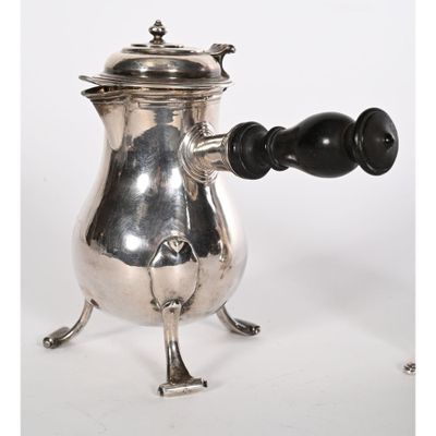 une cafetière ancienne en argent avec une poignée en bois sur un support