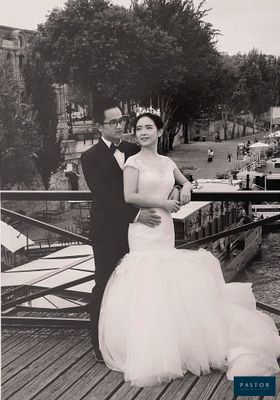 bride and groom posing for a photo on a bridge near a river