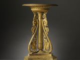 une table richement sculptée, dotée d'un piédestal, sur un fond blanc