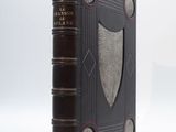 un vieux livre posé sur une surface blanche ornée d'un blason