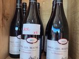 several bottles of wine sit in a wooden box on a shelf