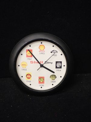 une horloge noire avec un cadran blanc et divers autocollants dessus