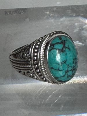une bague en argent sertie d'une turquoise, posée sur une table