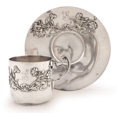 une tasse et une soucoupe en argent posées à côté d'une assiette