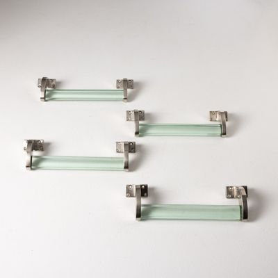 quatre étagères en verre avec des supports métalliques sur un plan de travail blanc