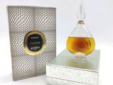 une image représentant un flacon de parfum posé sur un coffret en argent