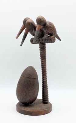sculpture en bois représentant deux pélicans perchés sur un arbre, avec un œuf au premier plan
