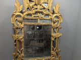une image représentant un miroir à cadre doré posé sur une surface blanche