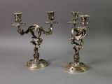 pair of silver candlesticks with flowers on each of them