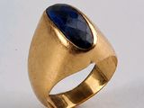 gros plan d'une bague en or avec une pierre bleue
