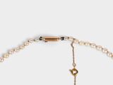 a close up of a pearl necklace with a gold clasp