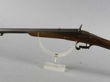 a rifle with a wooden barrel on a clear stand