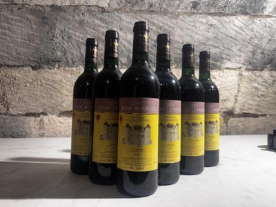 six bottles of wine are lined up on a table in front of a brick wall