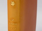 un livre orange posé sur une table près d'un mur blanc