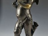 une statue en bronze représentant un petit garçon tenant une trompette