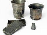 une coupe en argent et un récipient en argent posés sur une surface blanche