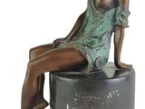 bronze statue of a woman sitting on a stool with her legs crossed