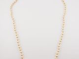 a gold beaded necklace with a single pearl bea