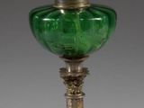 an antique silver and green glass oil lamp on a stand