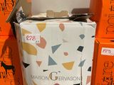 Plusieurs cartons de vin sont empilés les uns sur les autres par terre.