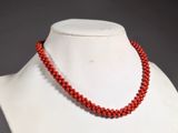 a close up of a necklace on a mannequin with red beads