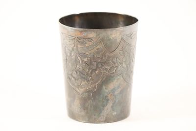 une tasse en métal ornée d'un motif sur un fond blanc